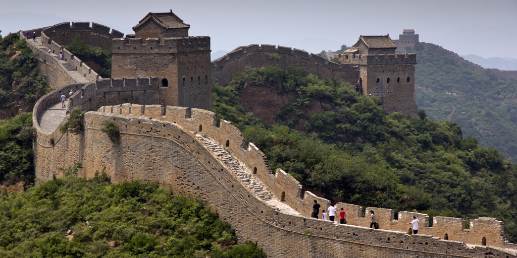 De Chinese Muur met wachttorens en wandelaars tussen groene heuvels in China.