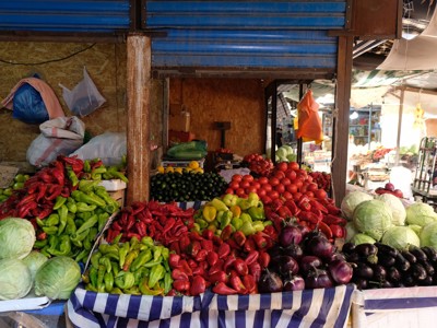 Groentestalletje op een markt langs de Route Zijderoute, met paprika’s, tomaten, aubergines en kolen.