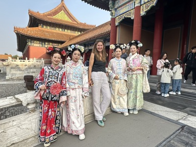 Toeristen poseren bij de Verboden Stad in Beijing, met vrouwen in kleurrijke hanfu voor een paleispoort.