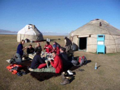 Reizigers eten buiten bij traditionele yurts tijdens de Route Zijderoute.