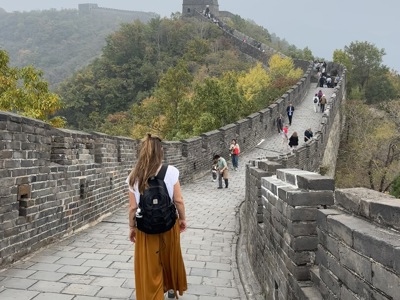 Wandelaar op de Chinese Muur met uitzicht op wachttorens en beboste heuvels.