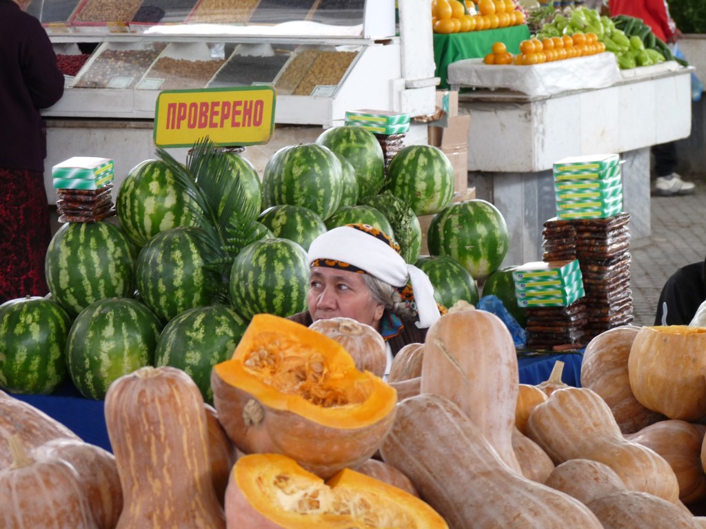 Markt op de Zijderoute met watermeloenen en pompoenen bij een kraam.