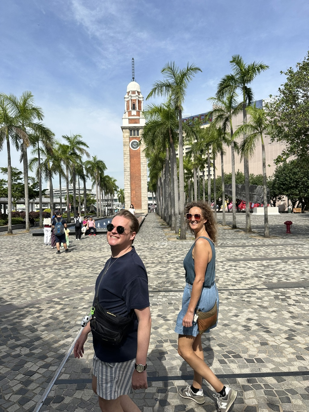 Toeristen wandelen langs palmbomen bij de Clock Tower op de Avenue of Stars in Hongkong.
