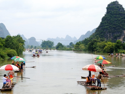 Bamboevlotten met kleurrijke parasols op de Li-rivier bij Guilin, met karstbergen op de achtergrond.