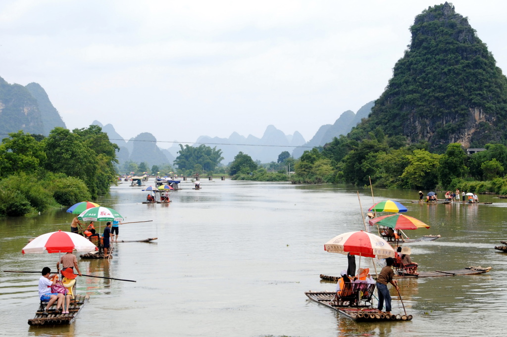 Bamboevlotten met kleurrijke parasols op de Li-rivier bij Guilin, met karstbergen op de achtergrond.