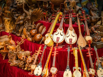 Traditionele snaarinstrumenten en houten dierenbeelden op een markt langs de Route Zijderoute.