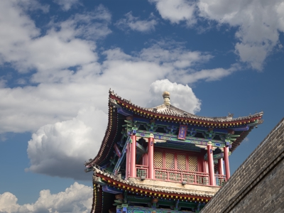 Traditionele Chinese wachttoren op stadsmuur langs de Route Zijderoute, met blauwe lucht en wolken.